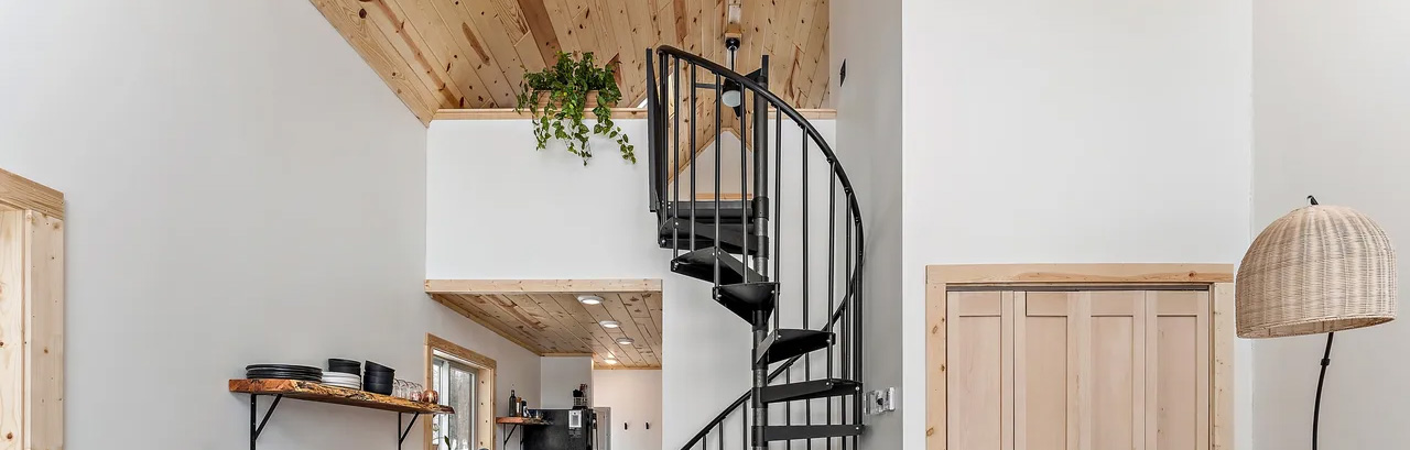 spiral stair going up to loft in light and airy cabin with limited interior space