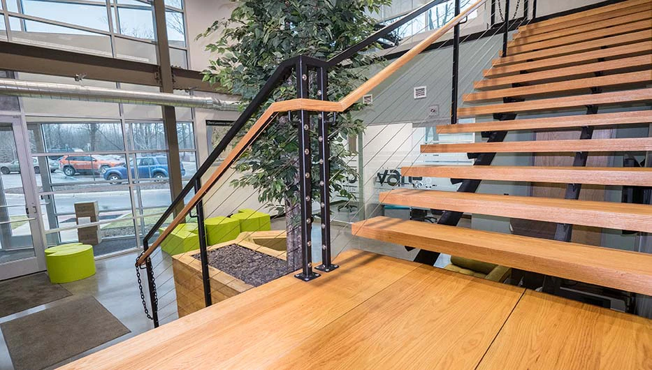 large dual stringer floating staircase with solid wood treads and handrail in a commercial office space foyer with large turn platform