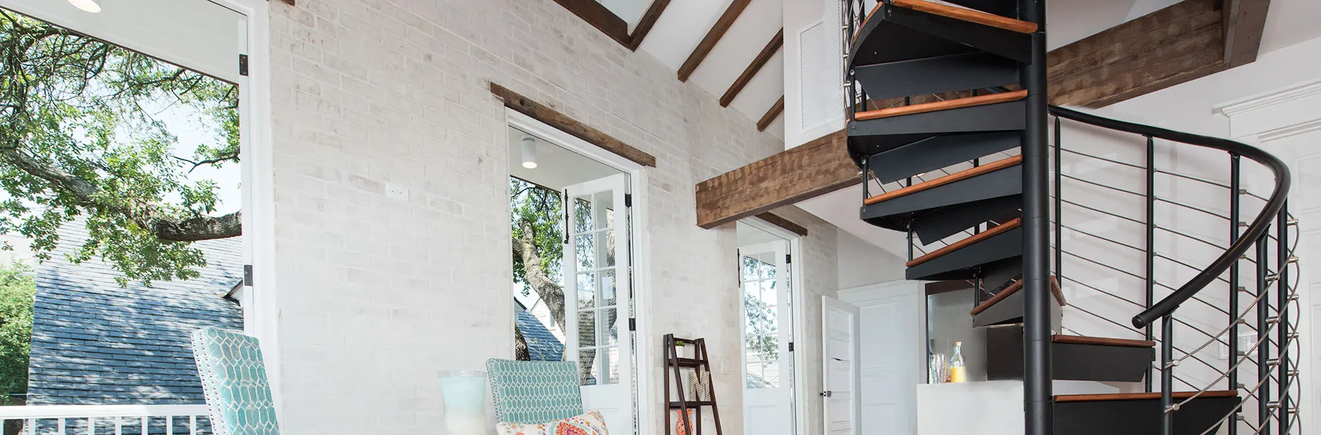 Paragon black steel spiral staircase with wood treads and cable railing installed in a small loft apartment.