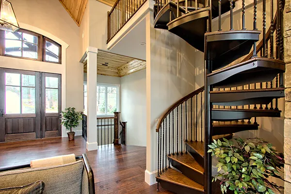 Traditional spiral staircase with wood treads and dark balusters placed near a front entry, highlighting an inviting architectural transition between levels.