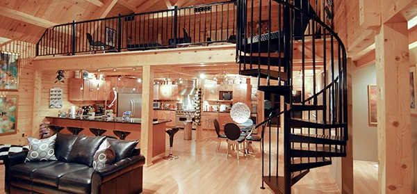steel spiral staircase in a post-and-beam barndominium interior with natural wood finishes.